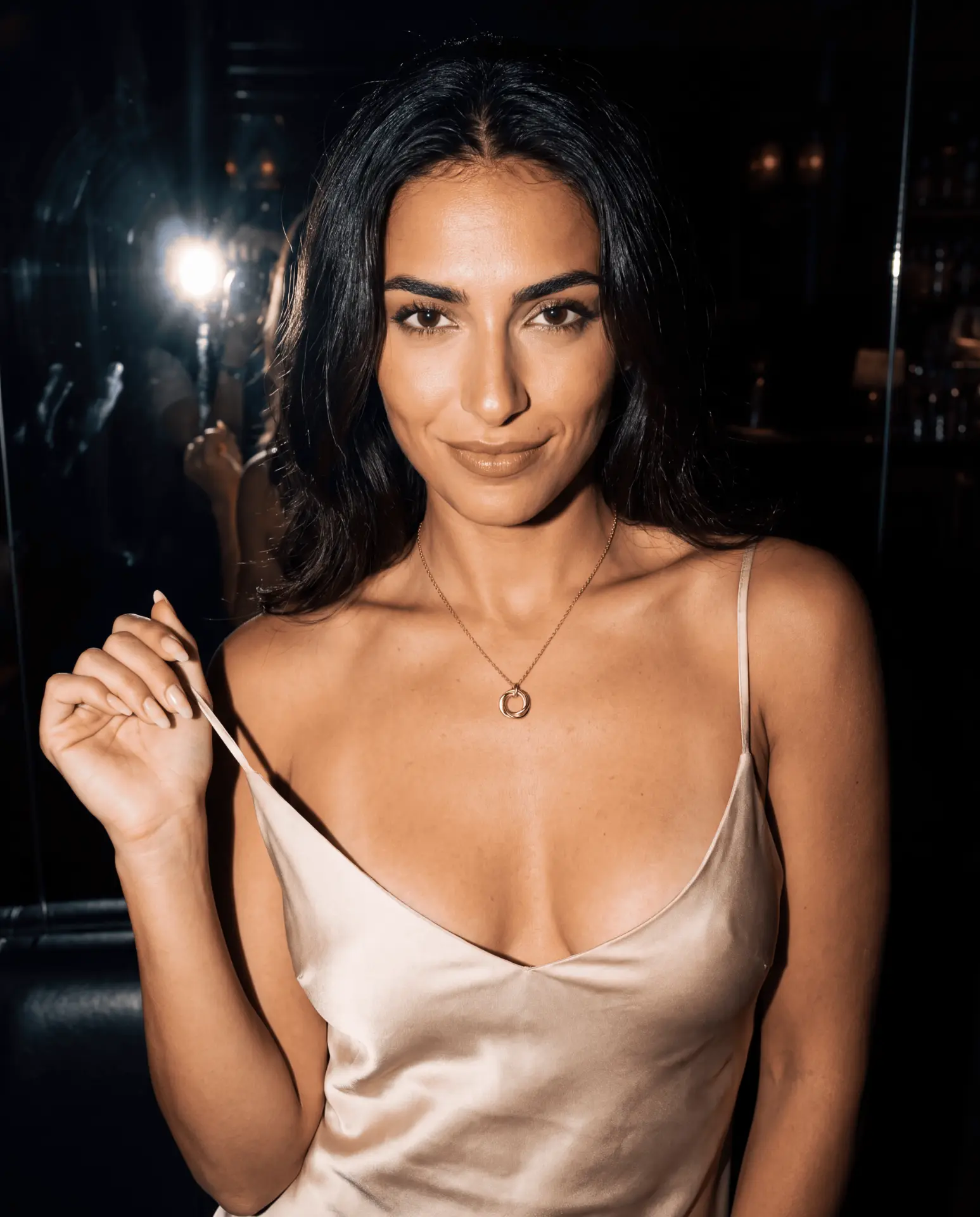 Model wearing a gold pendant and satin dress in warm evening light