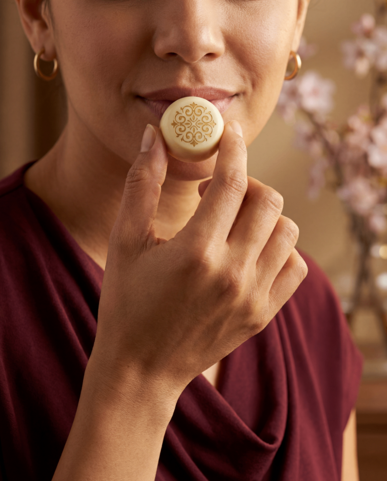 Vrouw houdt wit chocolaatje voor haar mond