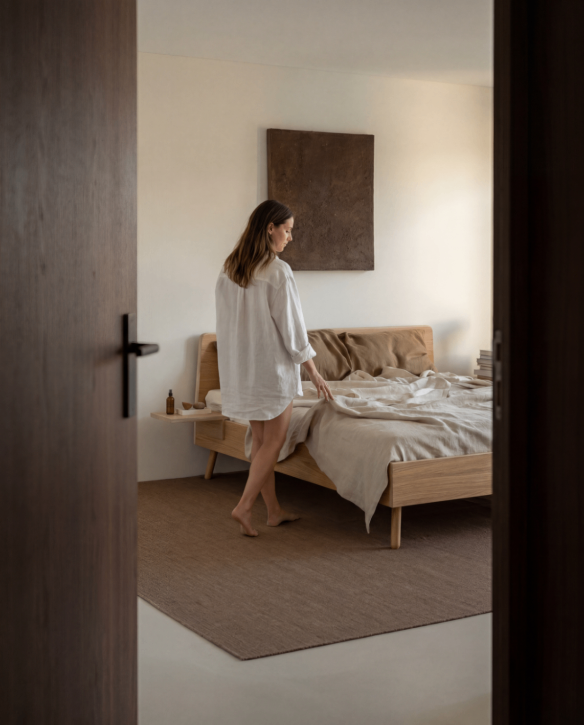 Slaapkamer gezien door deuropening met model naast bed